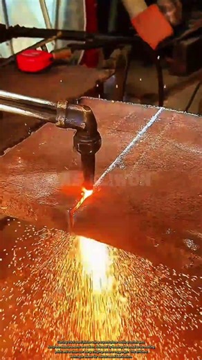Cutting thick steel plates using oxyacetylene welding techniques.